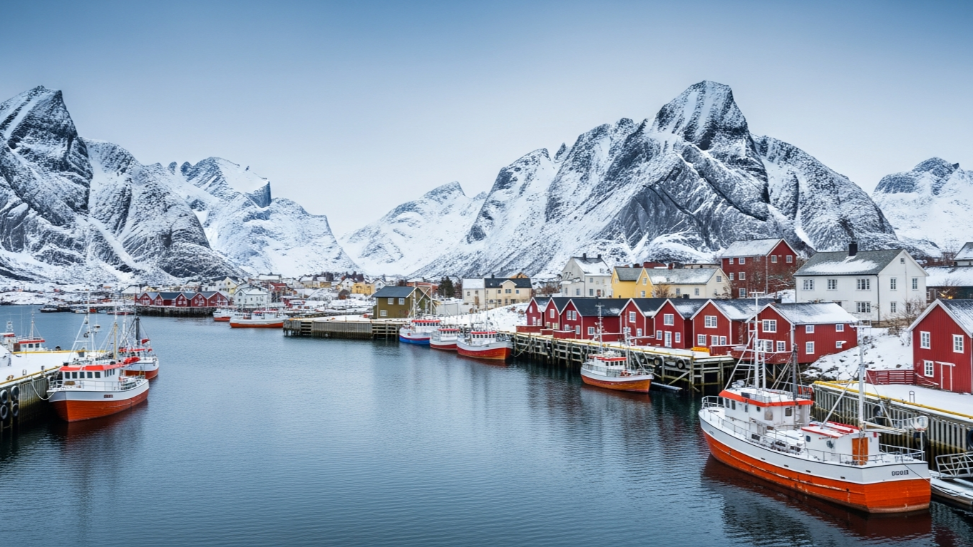 ท่าเรือ Tromsø ในฤดูหนาว เรือประมงไม้สีสันสดใสจอดเรียงรายพร้อมภูเขาหิมะในพื้นหลัง